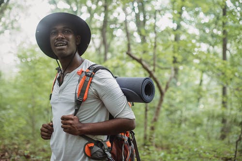 站立与迁徙的背包的正面黑人在森林里 · 免费素材图片