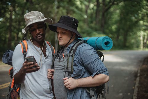 多种族的男性徒步旅行者共享乡村道路上的智能手机 · 免费素材图片