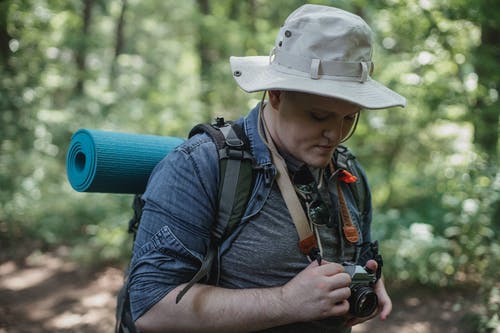 有照片照相机的男性远足者在森林里 · 免费素材图片