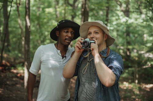 最好的多种族男性朋友与照片相机在森林里聊天 · 免费素材图片