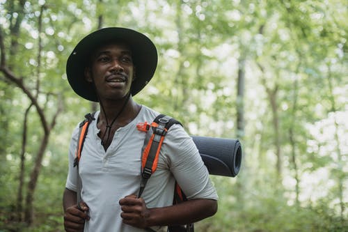 梦幻般的黑人男性旅行者背包在树林里 · 免费素材图片