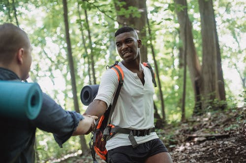 非裔美国人的远足者帮助人爬上 · 免费素材图片