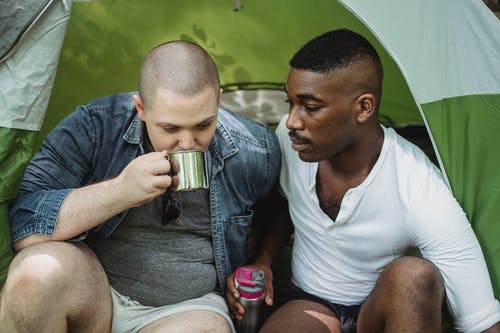 男人从保温瓶里坐着黑人朋友喝茶 · 免费素材图片