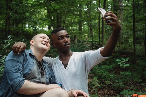 同性恋夫妇拥抱和采取自拍照在森林里 · 免费素材图片