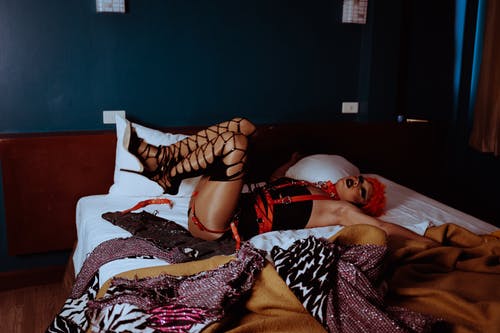 躺在床上抬起双腿的非正式男性变性者 · 免费素材图片