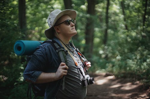 太阳镜探索夏季树林的男性背包客 · 免费素材图片