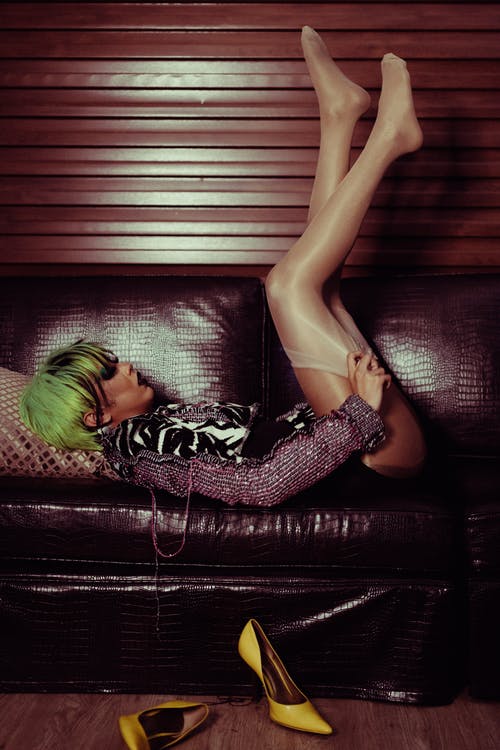 诱人的女人躺在沙发上，双腿引诱着 · 免费素材图片