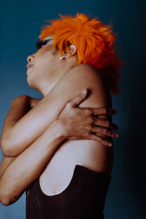 体贴的年轻雌雄同体男人用手覆盖乳房在蓝色工作室 · 免费素材图片