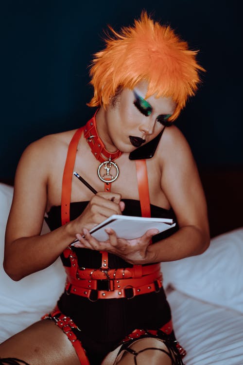 Bdsm服装的诱人的年轻变性人谈话在智能手机和做笔记 · 免费素材图片