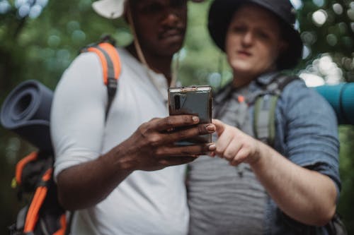 在夏季旅行期间，多种族旅行者共享智能手机 · 免费素材图片