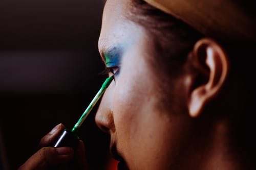 亚洲女人在眼皮上应用明亮的眼影 · 免费素材图片