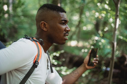 背包和智能手机在森林里的黑人男子 · 免费素材图片