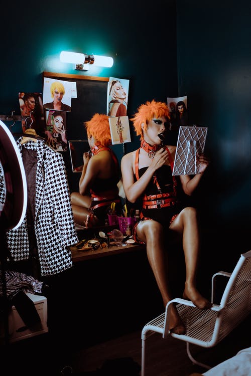 年轻的变性人在舞台上的衣服坐在更衣室里的镜子桌上 · 免费素材图片