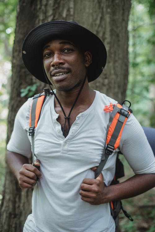 微笑在树林里背囊的非洲裔美国旅行者 · 免费素材图片