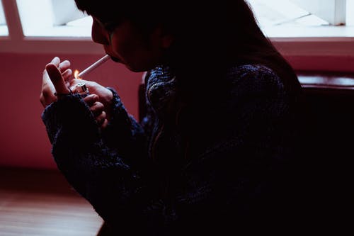 女人在黑暗的房间里吸烟 · 免费素材图片
