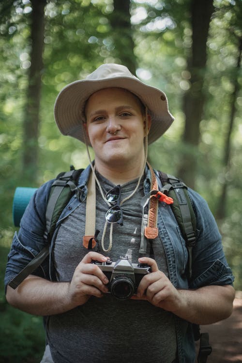 有照片照相机的微笑的旅客在森林 · 免费素材图片