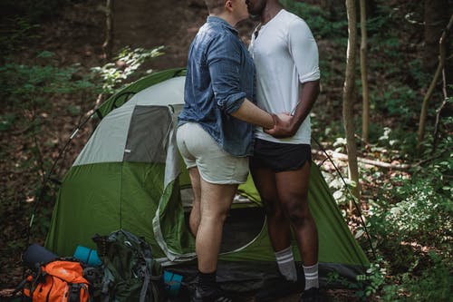 幸福的同性恋情侣接吻在森林里的帐篷附近 · 免费素材图片