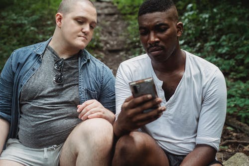 沉思的朋友在白天浏览森林中的智能手机 · 免费素材图片