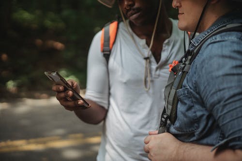 作物多种族背包客在巷道上的智能手机上浏览互联网 · 免费素材图片