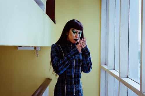 人体艺术在窗口附近的脸上香烟的时尚亚洲女人 · 免费素材图片