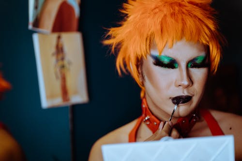 种族的雌雄同体年轻人在试衣间应用口红的怪异化妆 · 免费素材图片