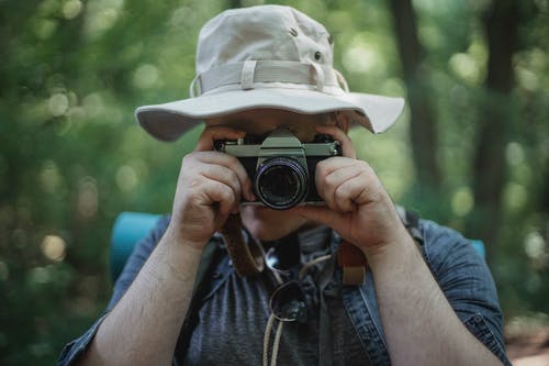 在树林里的相机上的匿名游客拍照 · 免费素材图片