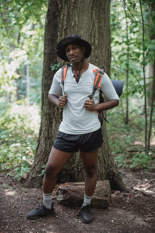 在森林里的树附近的非洲裔美国背包客 · 免费素材图片