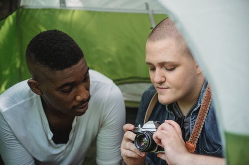 聚焦年轻人向男性朋友展示复古照片相机 · 免费素材图片