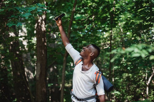 性格开朗的黑人，在森林里的智能手机上有信号 · 免费素材图片