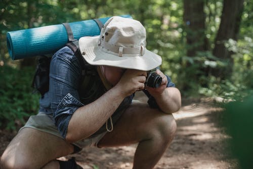 在森林里的相机上拍照的匿名背包客 · 免费素材图片