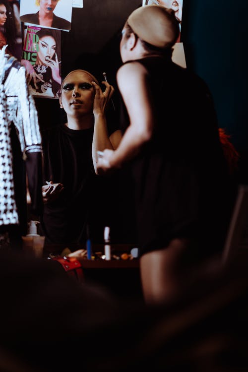 看着镜子时做化妆的创意族裔女人 · 免费素材图片