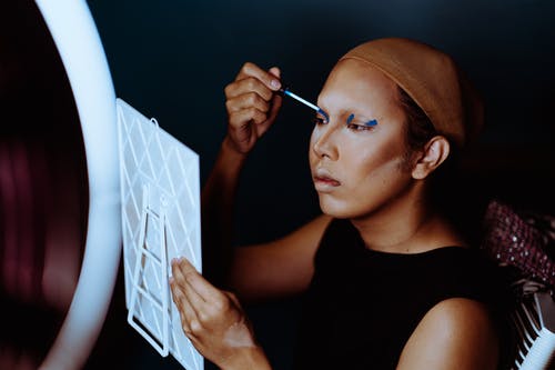 亚裔女子和假发帽应用明亮的眼影 · 免费素材图片