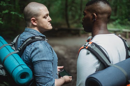 与智能手机站在森林中的路径上的多样徒步旅行者 · 免费素材图片