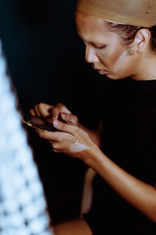 有基础的亚裔妇女在面孔检查在智能手机的消息 · 免费素材图片