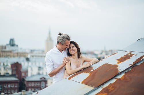 拥抱在城市屋顶上的新人面带笑容 · 免费素材图片