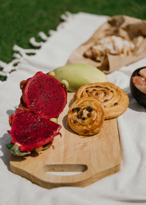 木砧板上的火龙果片和羊角面包 · 免费素材图片