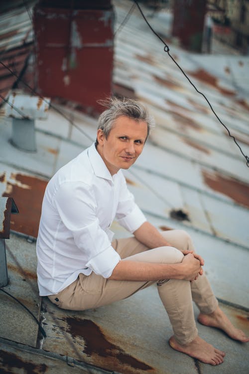 时尚的男人坐在建筑物的屋顶上 · 免费素材图片