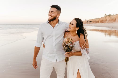高兴新婚夫妇在海滩上行走 · 免费素材图片