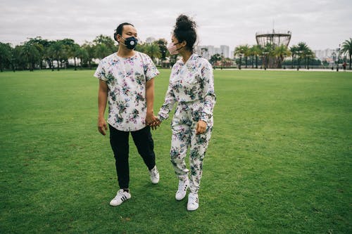 情侣与口罩站在绿草地上 · 免费素材图片
