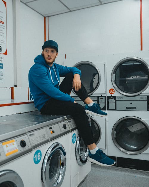 蓝色长袖衬衫和黑色的裤子，坐在前面的洗衣机上的男人 · 免费素材图片