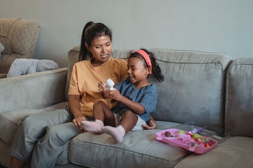 亚洲母亲和女儿在沙发上的玩具 · 免费素材图片