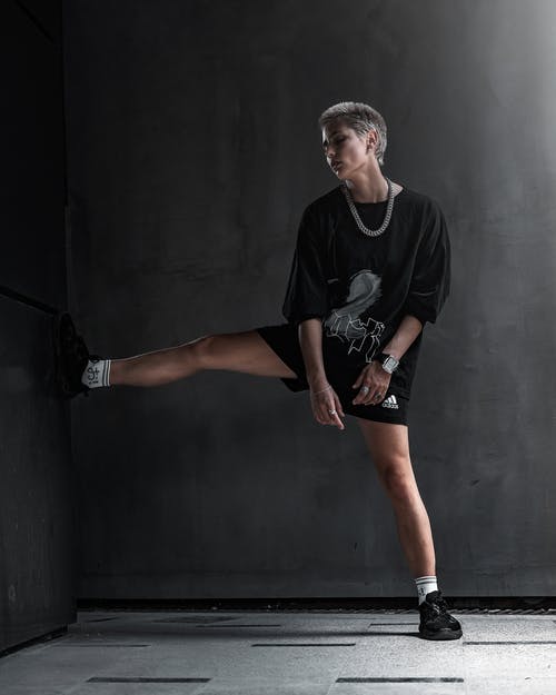 雌雄同体的女人，脚靠在灰色的墙上 · 免费素材图片