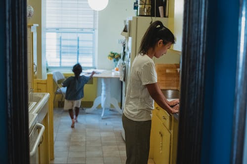 亚裔母亲和女儿在有蓝色门道入口的厨房里 · 免费素材图片