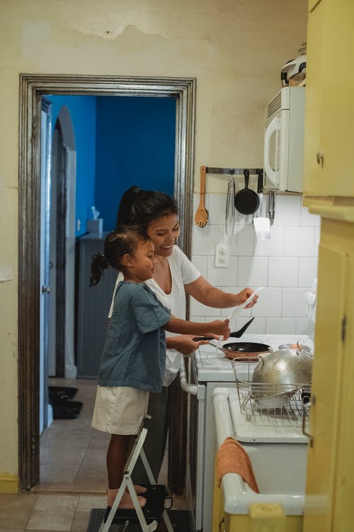 有女儿的微笑的妇女在厨房里 · 免费素材图片