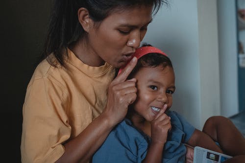 美满的亚洲母亲和女儿用手指靠近嘴唇 · 免费素材图片