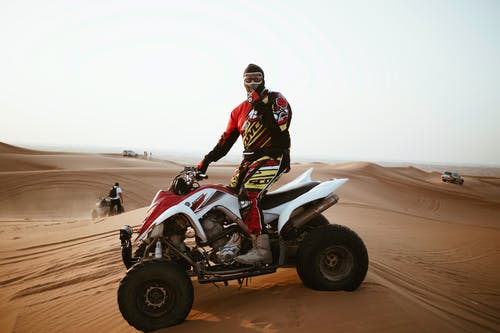 头盔在沙漠中的四轮摩托的人 · 免费素材图片