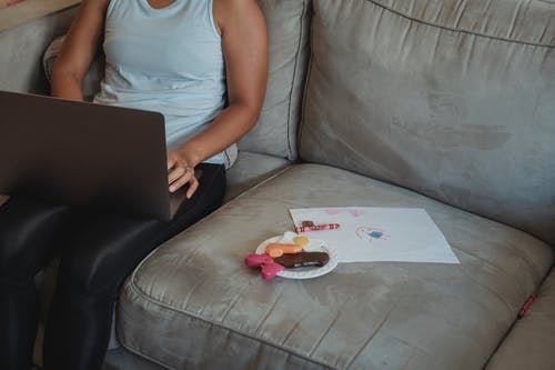 作物母亲在沙发上使用笔记本电脑 · 免费素材图片