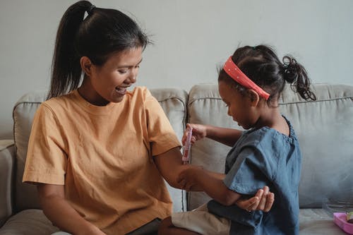 族裔母亲和女儿玩玩具注射器 · 免费素材图片