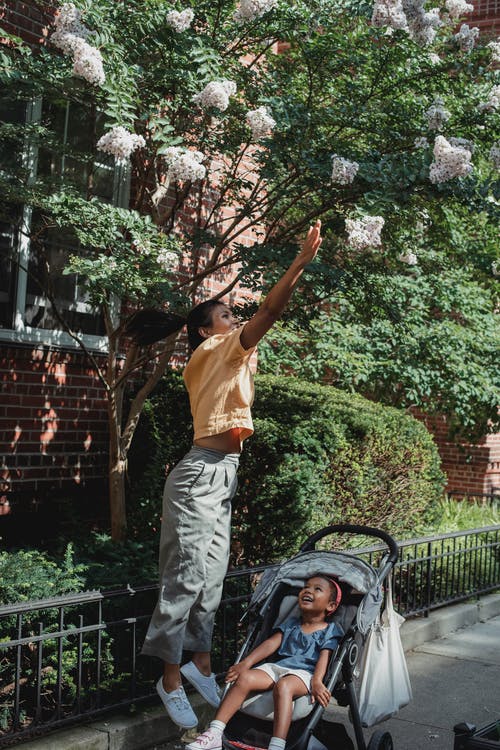 族裔女人带着女儿在马车上到达街上的花 · 免费素材图片