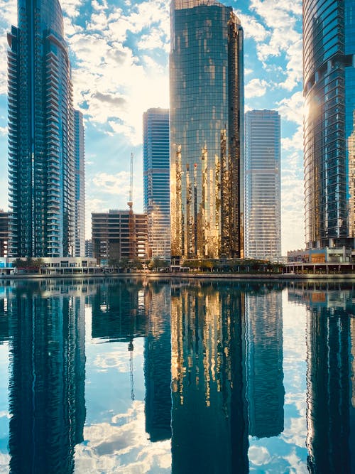 现代市区与反映在池塘里的摩天大楼 · 免费素材图片